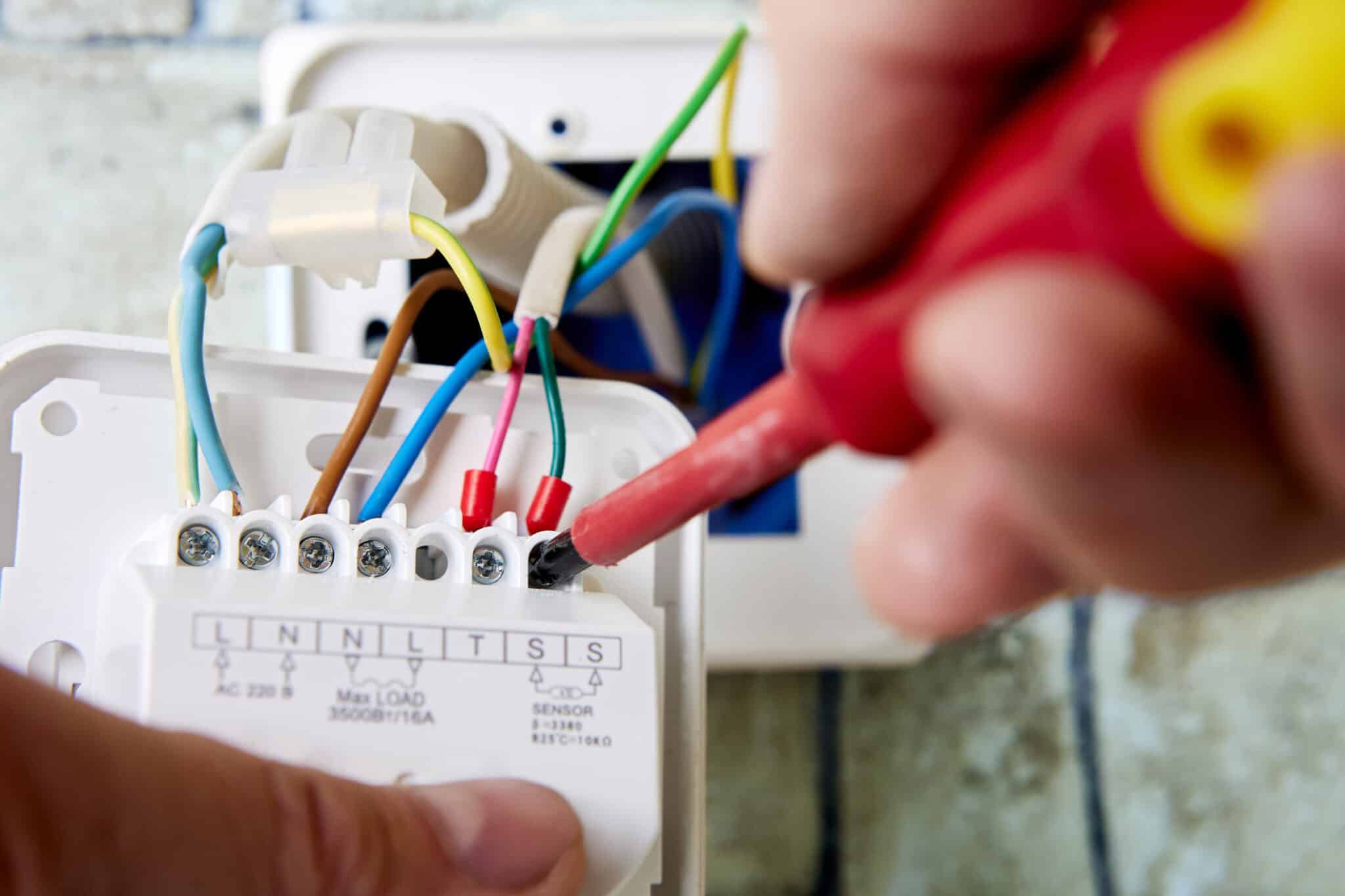 An electrician connecting colored wires to wall terminals. Electrical Remodeling by Mister Sparky of Charleston