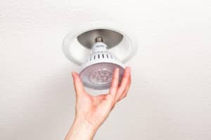 Hand Installing an IC-Rated LED Light Bulb into a Ceiling Fixture.