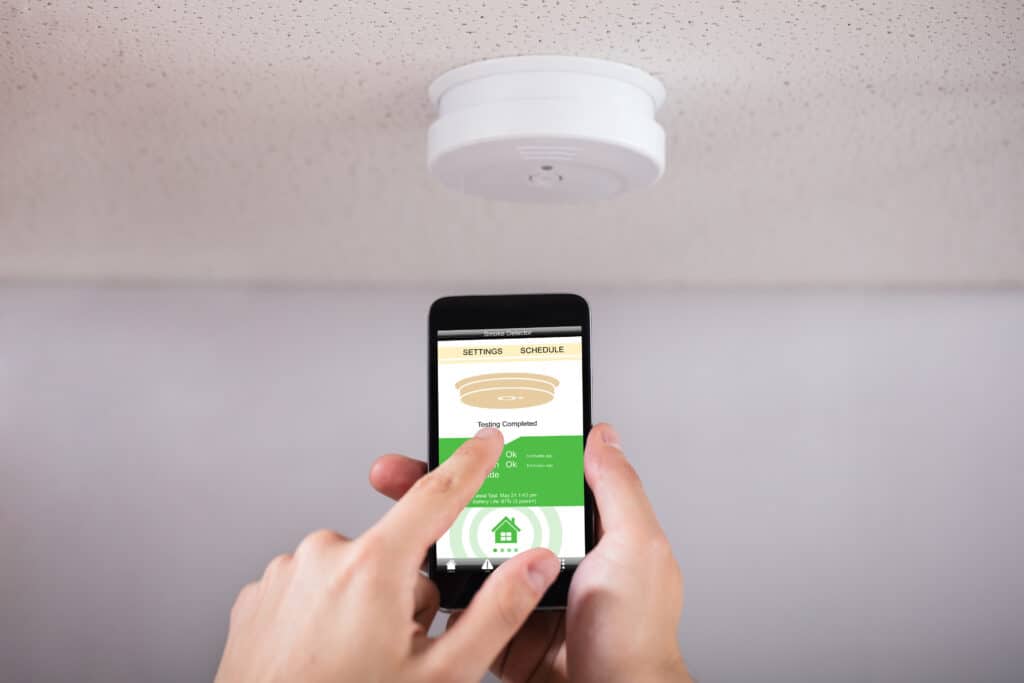 A Person Operating a Smart Smoke Detector with a Mobile Phone.