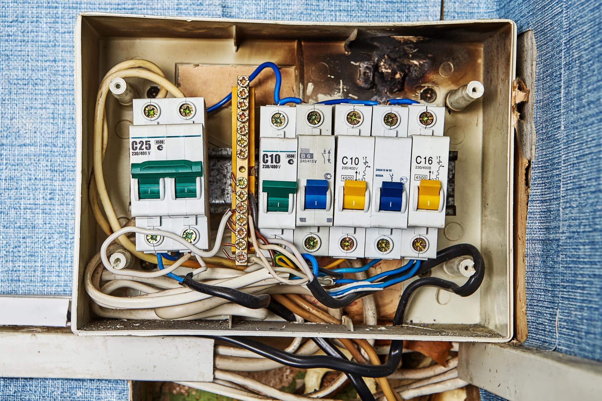 In a residential building, there are electrical problems, including an old, burned electrical switchboard and malfunctioning circuit breakers.