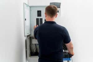 An electrician working on home electrical monitoring systems.